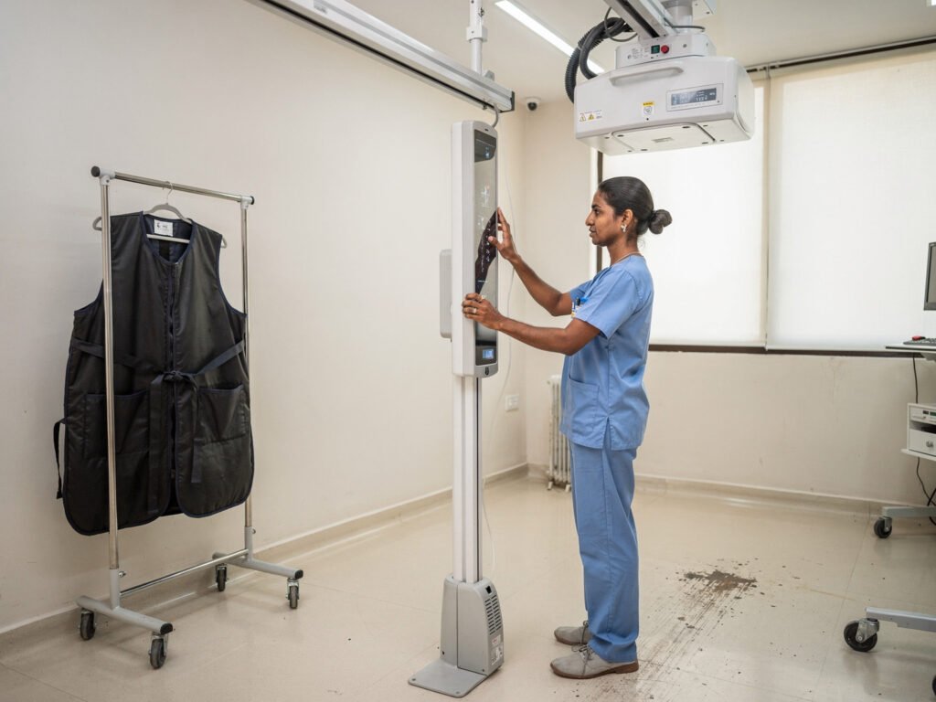 A digital X-ray room with a radiographer and detector panel